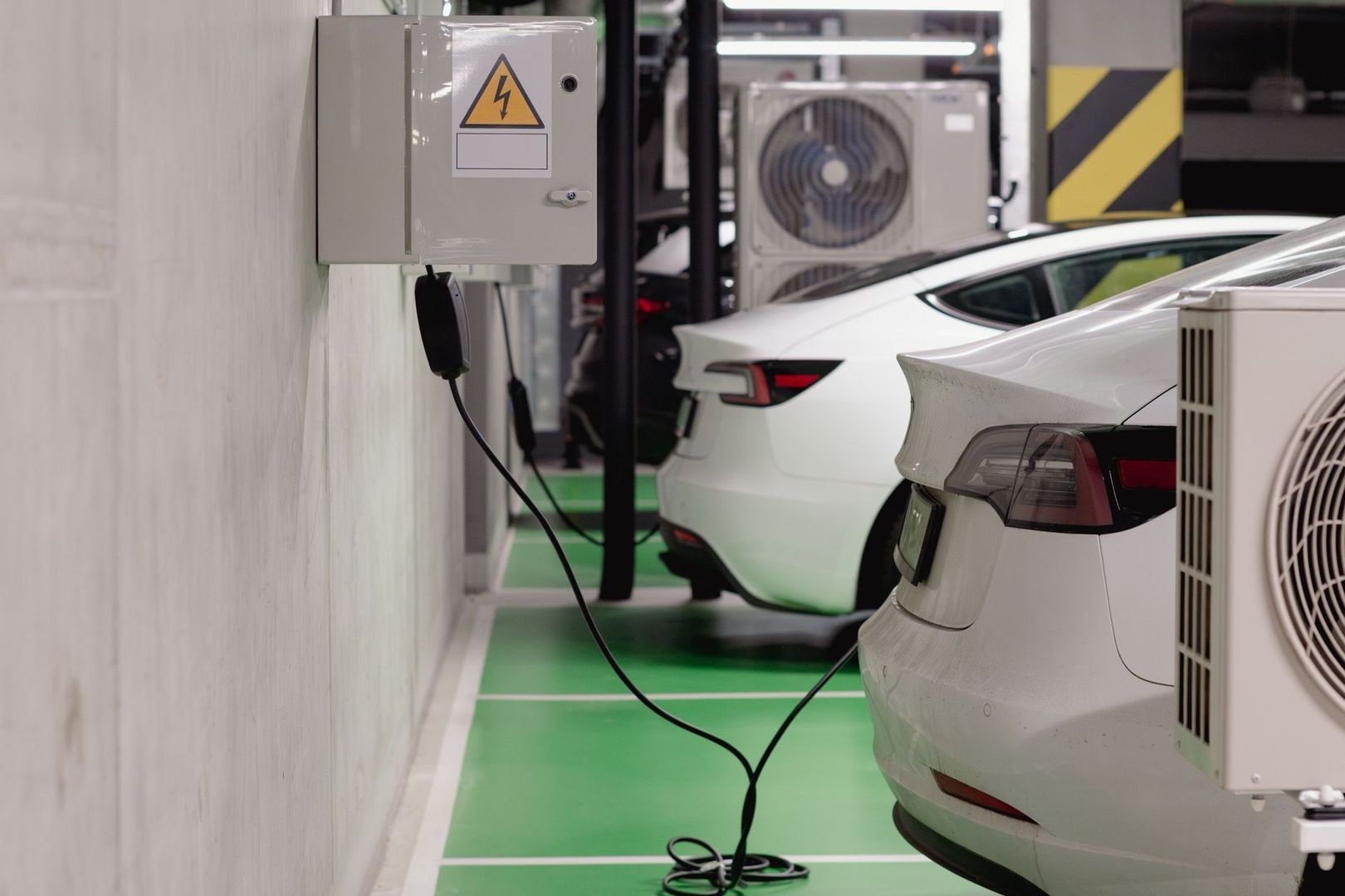 Elbilar parkerade i rad med laddkabel i ett garage