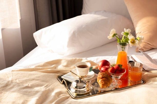 Frukostbricka med kaffe, juice, frukt och bakverk på en säng