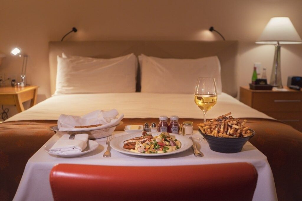 Room service med vitt vin och middag serverad framför en hotellsäng