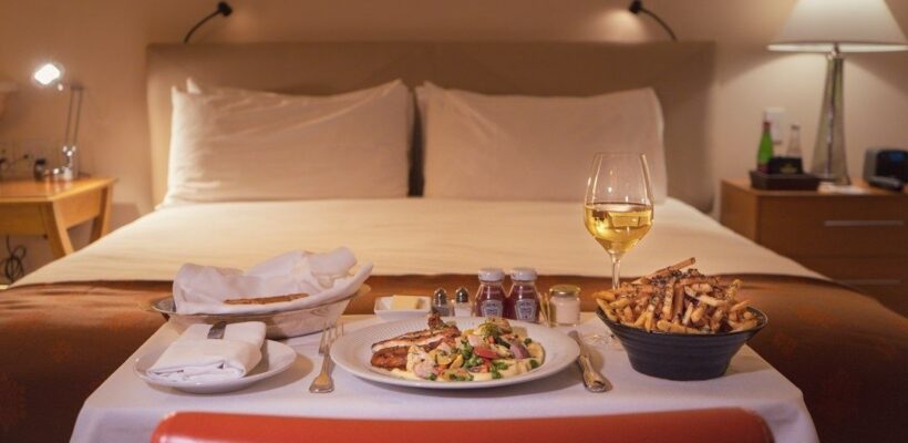 Room service med vitt vin och middag serverad framför en hotellsäng