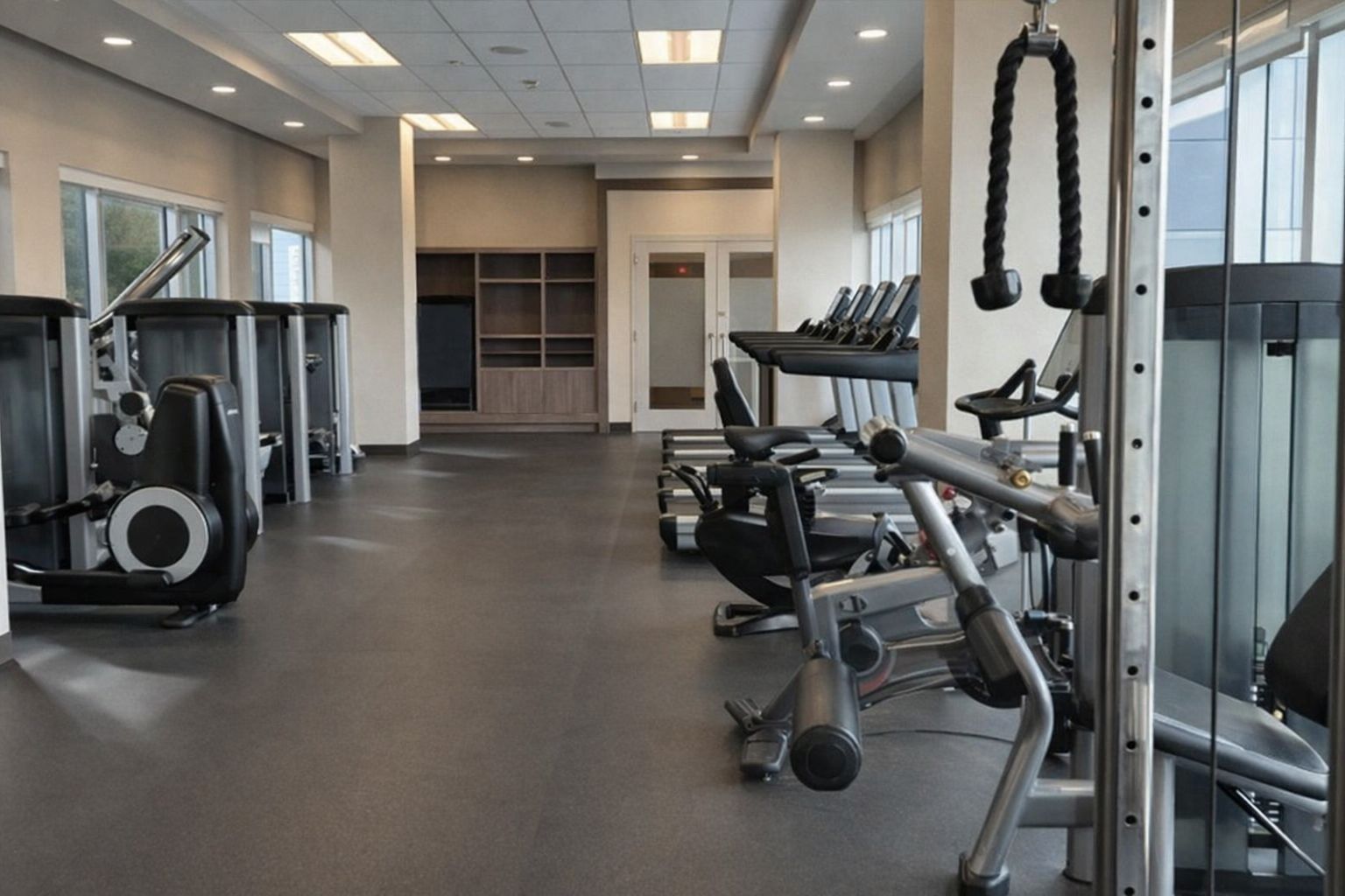 Ljust hotellgym med löpband, träningscyklar och styrketräningsmaskiner.
